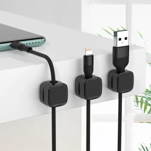Three black magnetic cable clips organizing charging cables along the edge of a white desk